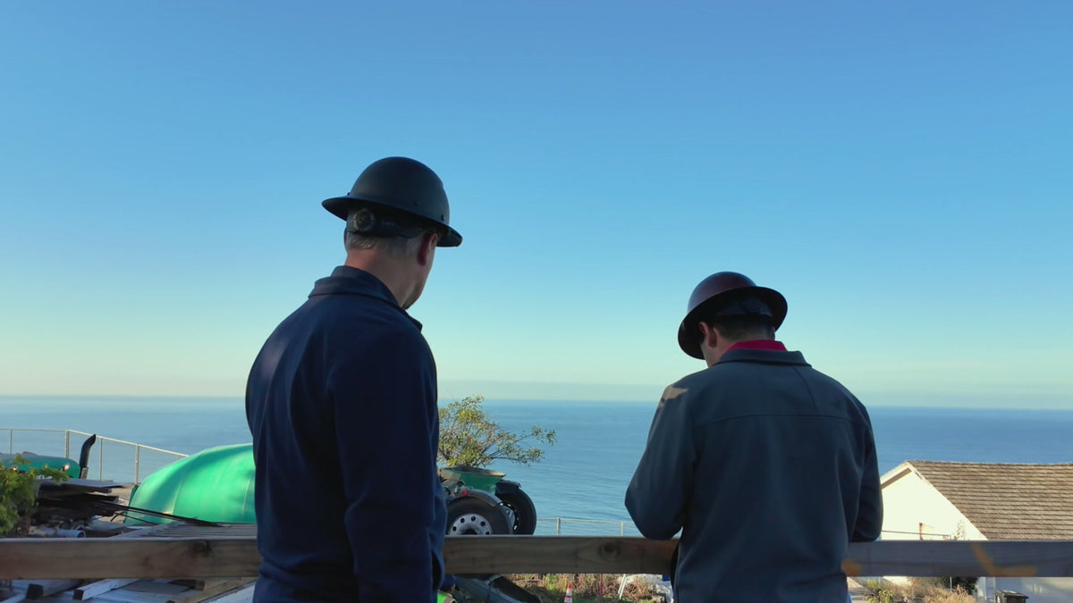 Two workers reviewing work at a coastal construction site